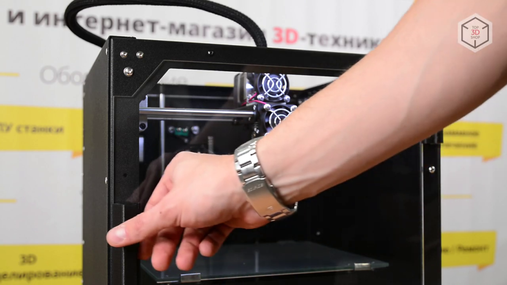 Корпус 3D-принтера открыт сверху, но фронтальный доступ к рабочему пространству закрыт прозрачной пластиковой дверцей